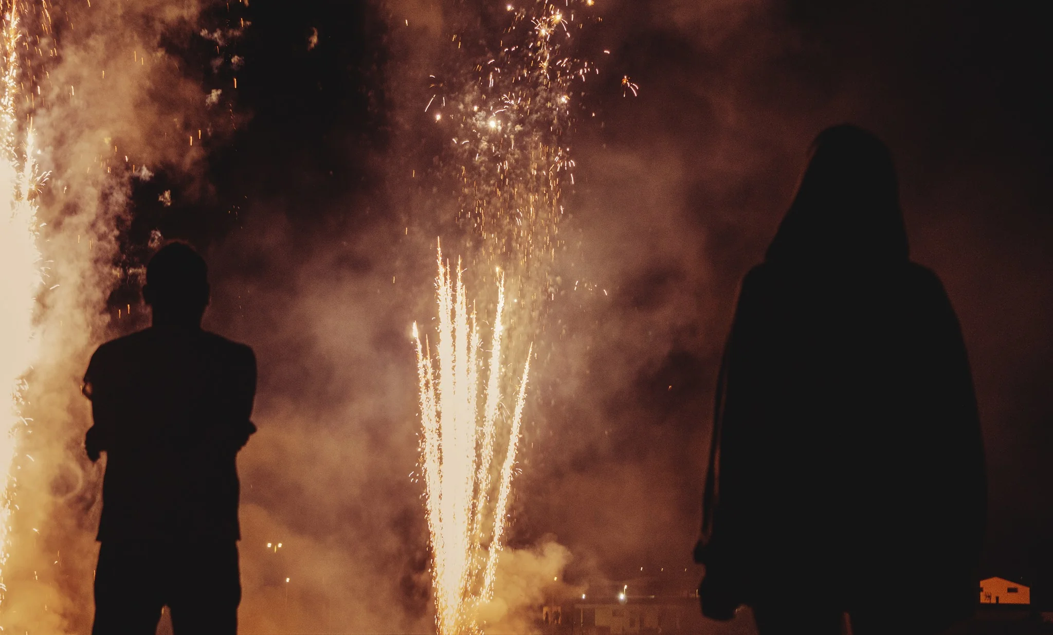 Due sagome in controluce osservano i fuochi d'artificio nella notte della festa